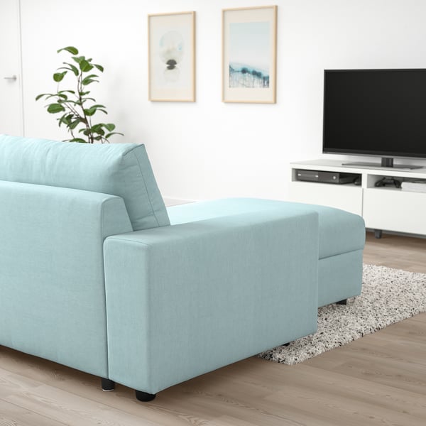 Light blue VIMLE sofa section, modern design, light wood floor, white walls, tv, art frames, plant.