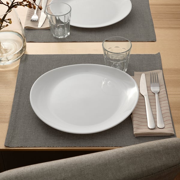 VITBLECKA opal glass plates and cups on grey placemats with cutlery. Plates are large, set for dining. Elegant, shiny, and durable.