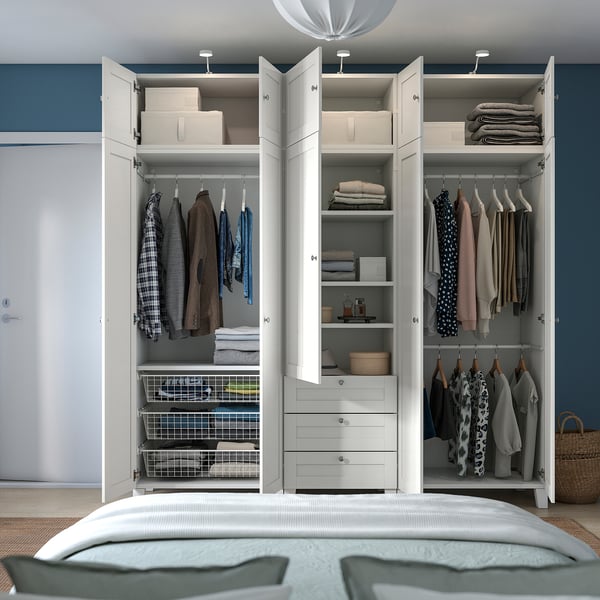 Bedroom closet organised with clothes, shelves, drawers, and a flexible ceiling lamp offering focused illumination.