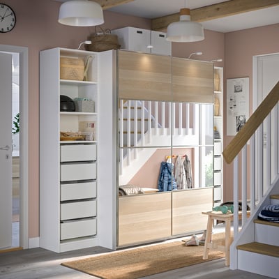 Modern bedroom a white YTBERG cabinet lamp illuminating an organised closet with drawers and shelves.