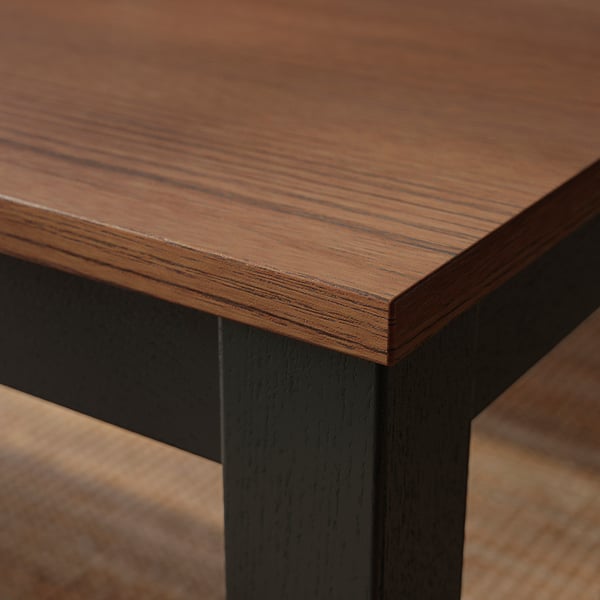 Close-up of wooden table edge, polished with clear finish, showing fine wood grain texture.
