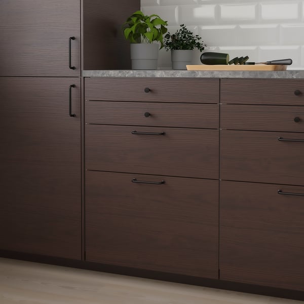 Modern kitchen with dark brown cabinets, plants, and wooden countertop. Sleek design, white backsplash.