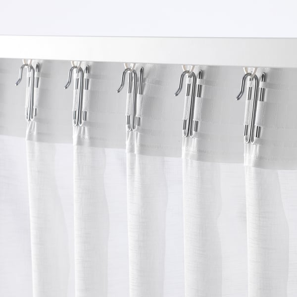 White sheer curtains hang with ASKKLOCKA hooks, diffusing light and offering subtle privacy.