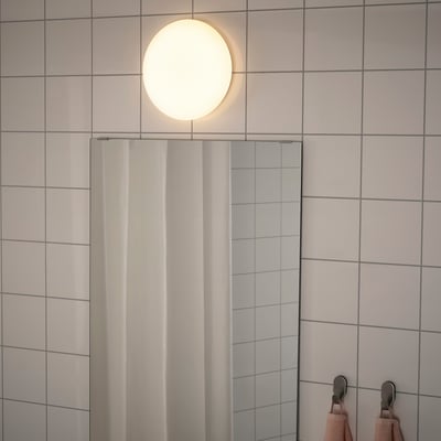 Modern bathroom with tiled walls, ceiling light, mirrored reflection, and towel hooks.