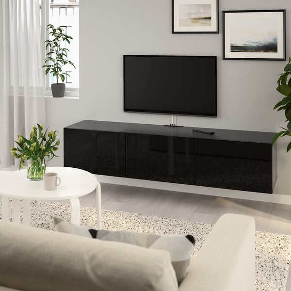 Modern living room with BESTÅ black tv bench, flat-screen tv, white side table, light sofa, plant, art.