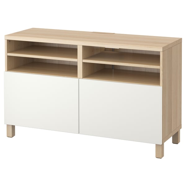 A BESTÅ tv bench in light oak and white. It open shelves and cabinetry for storage, with a minimalist design.