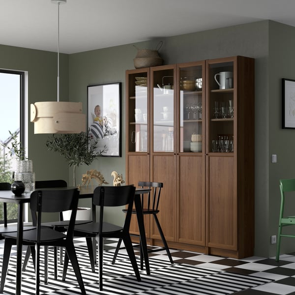 Dining room with BILLY bookcase & cabinet, brown, black chairs, striped rug, green walls, hanging light.