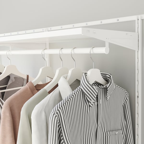 Closet with shirts on hangers, showing organised clothes storage with white shelves and rods.