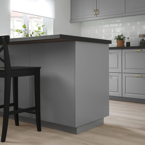 Grey bodby kitchen island with dark counter & stools, white cabinets, light wood floor.