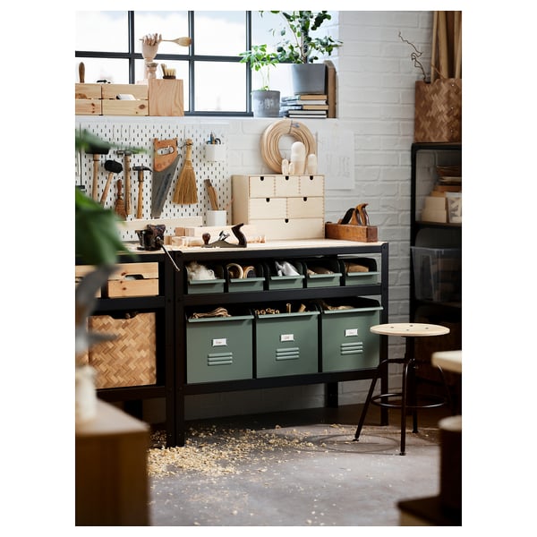 BROR black metal workbench with green bins, storing tools, surrounded by plants and decor in a well-lit room.