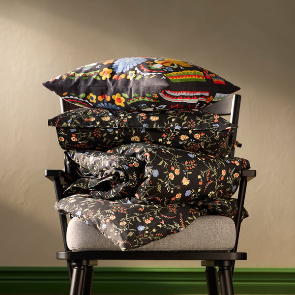 BRUDKRUSBÄR pillows: black, flowery, stacked on chair, plush, large