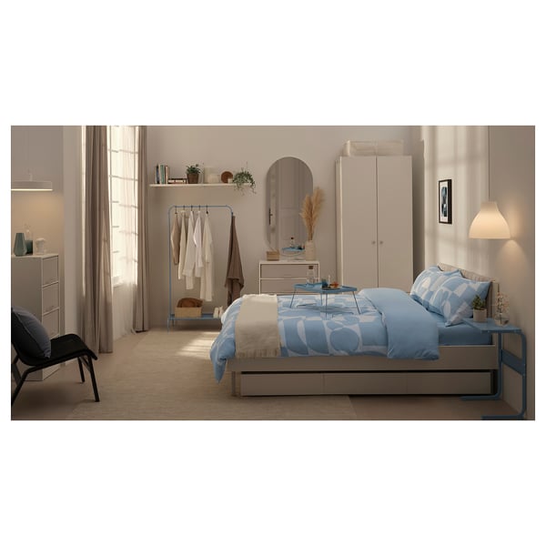 Modern bedroom with blue bedding, a clothes rack, and neatly arranged decor.