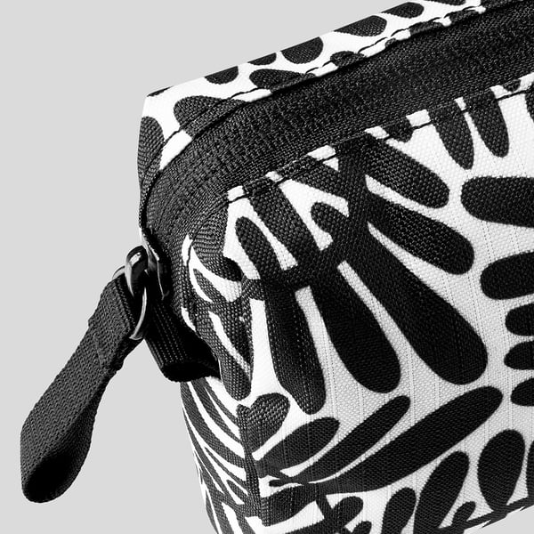 Black and white patterned backpack with a pull zip, shown in close-up view highlighting fabric quality.