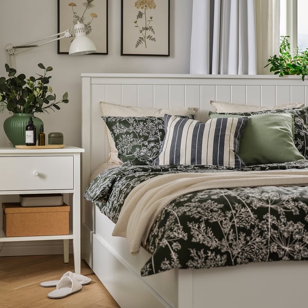Cosy bed with green/white DAGGBJÖRNBÄR duvet, striped pillows, flowers & slippers.