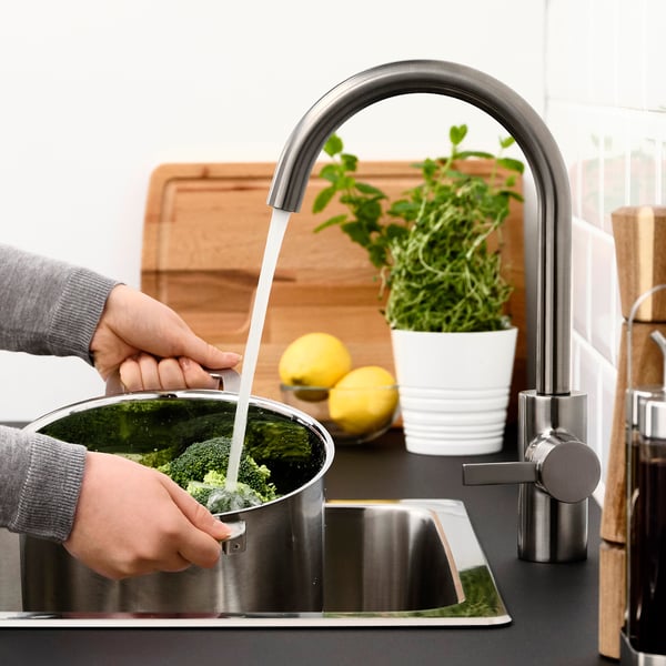 Person washing broccoli under DELSJÖN high arc tap.
