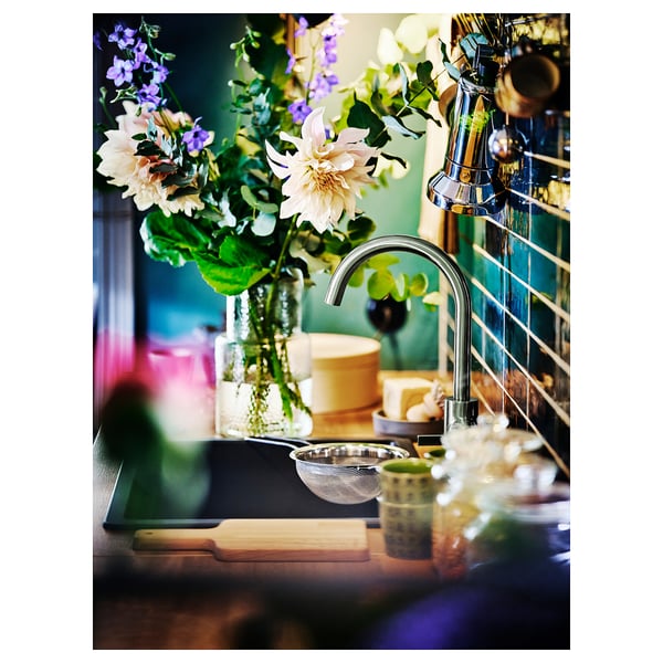 Kitchen counter with DELSJÖN pewter tap, flowers, cutting board, and drainer.