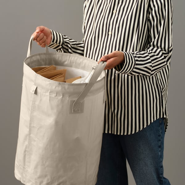 Person holding a large, foldable DIMPA bag with multiple compartments, ideal for sorting laundry or waste.