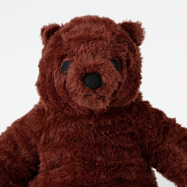 Soft, plush teddy bear with dark brown fur, stitched green eyes and nose, sitting upright.