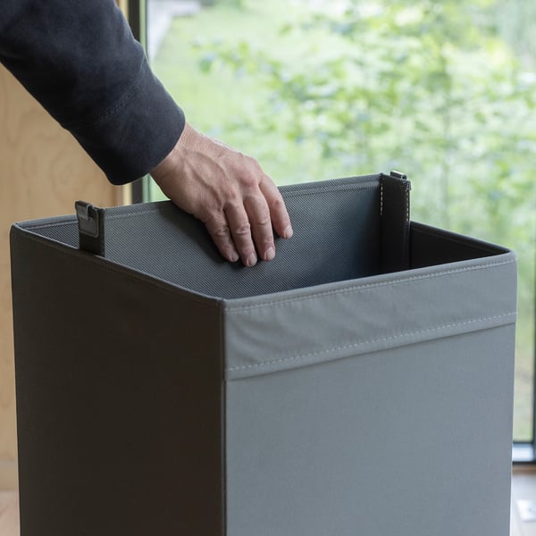 Hand placing a divider inside a grey storage box, organising compartments.