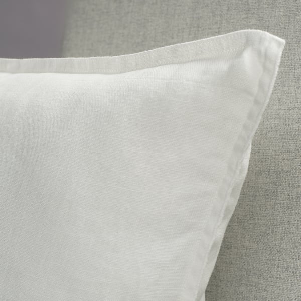 Close-up of crisp, white linen cushion cover on textured fabric, showcasing soft texture and neat stitching.