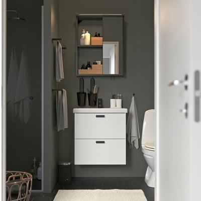 Modern bathroom with white ENHET wall cabinet, mirror, sink, and toilet. Towels hang nearby.