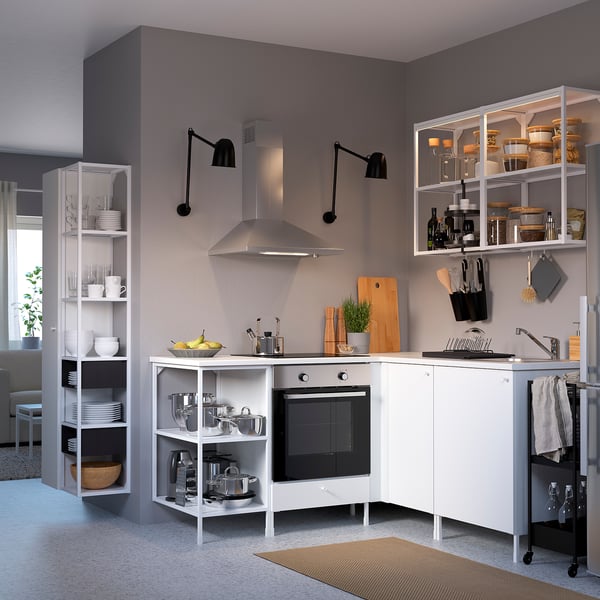 Modern kitchen with white ENHET storage. Cabinets & shelves hold dishes, pots, & utensils. Stainless steel hood & black accents. Spacious & organised.
