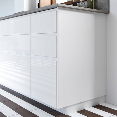 A white FÖRBÄTTRA kitchen cabinet with glossy surfaces and grey countertop, reflecting a minimalist style.