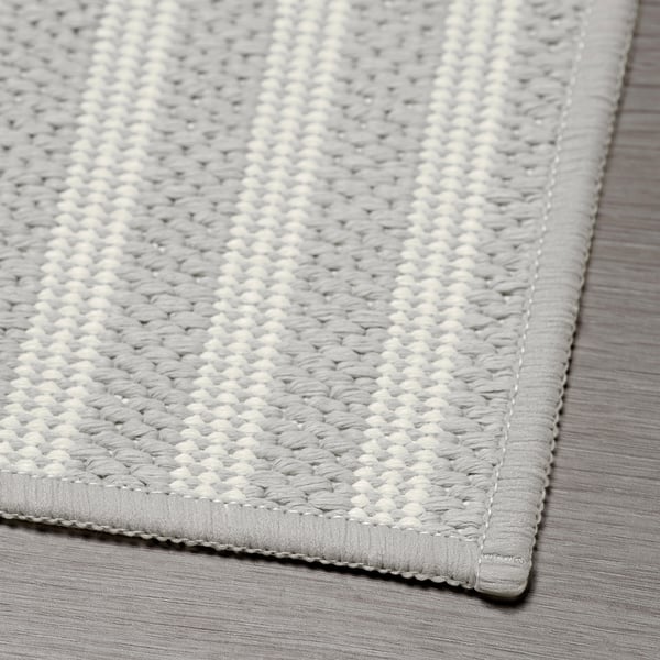 Grey chequered kitchen mat, well-crafted with stitched edges, laid on a striped surface.