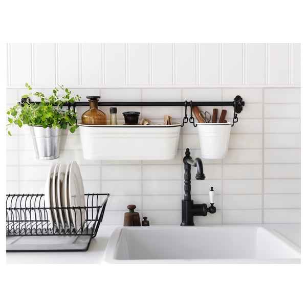 Kitchen with white sink, black tap, hanging plants, and dish rack.