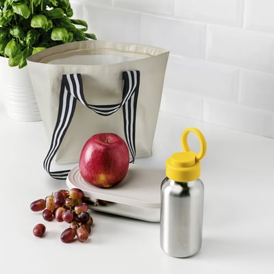 Beige GÖRSNYGG tote with black handles on counter, with fruit and water bottle.