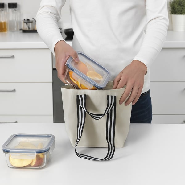 Person holding small GÖRSNYGG bag with transparent food container. Kitchen counter and cabinets in background.