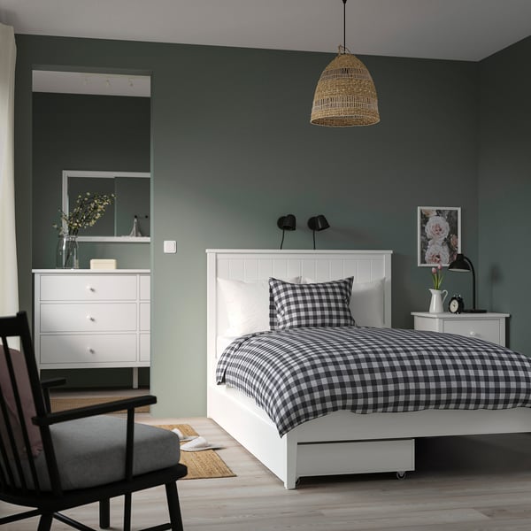 Minimalist bedroom: green walls, black/white bedding, white gullberg bed, black chair, rattan lamp, white dresser, mirror.