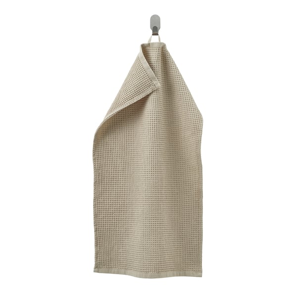 Light beige waffle-weave towel hangs on hook. Made from recycled cotton, its absorbent and quick-drying.
