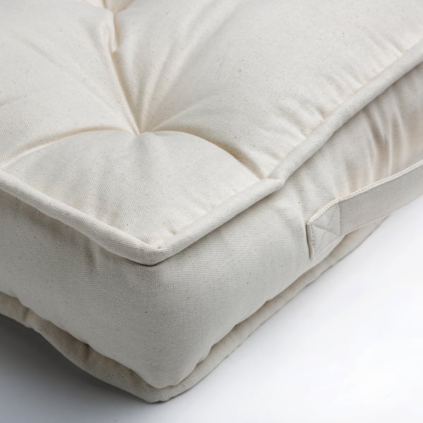 Close-up of white, textured floor cushion with even stitching and plush fabric.