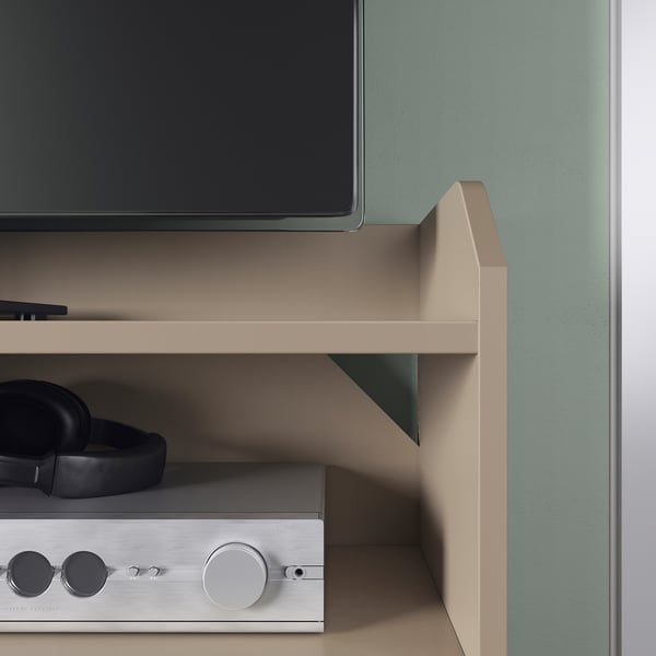 Modern tv stand with sleek design, black headphones, and a silver electronic device on its shelves.