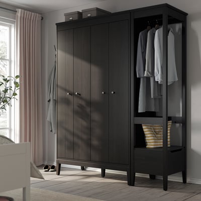 An IDANÄS wardrobe in black, showcasing both closed and open sections for clothes storage.