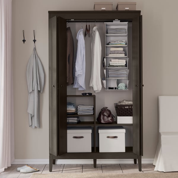 Dark wooden wardrobe with organised clothes, towels, and accessories.