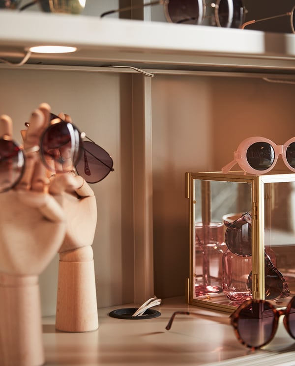 Display of stylish sunglasses on modern, minimalist mannequins and glass shelves, featuring various designs and colours.