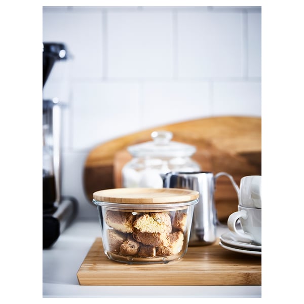 IKEA 365+ glass jar with bamboo lid filled with cookies on a wooden board.