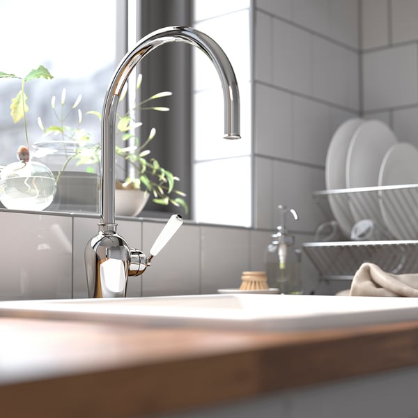 Modern kitchen sink with INSJÖN chrome tap, high spout. Sits above clean counter with drying rack and plant. Efficient, shiny, and sleek.