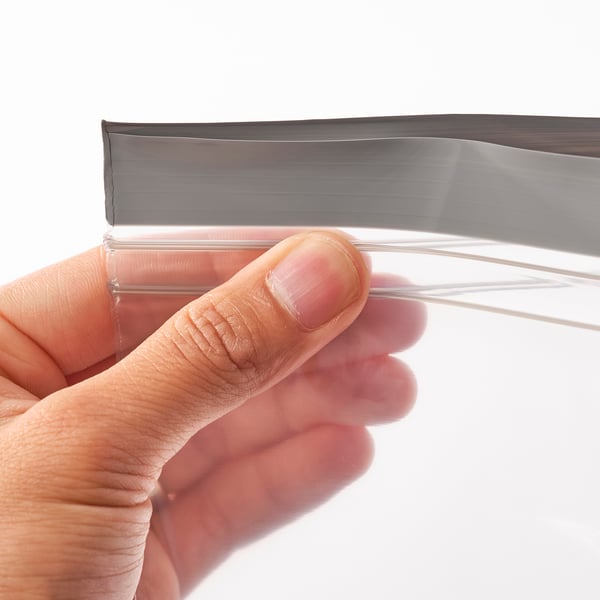 A hand holding an ISTAD bag, demonstrating its resealable zip, showing its functionality in storing and sealing food to keep it fresh.