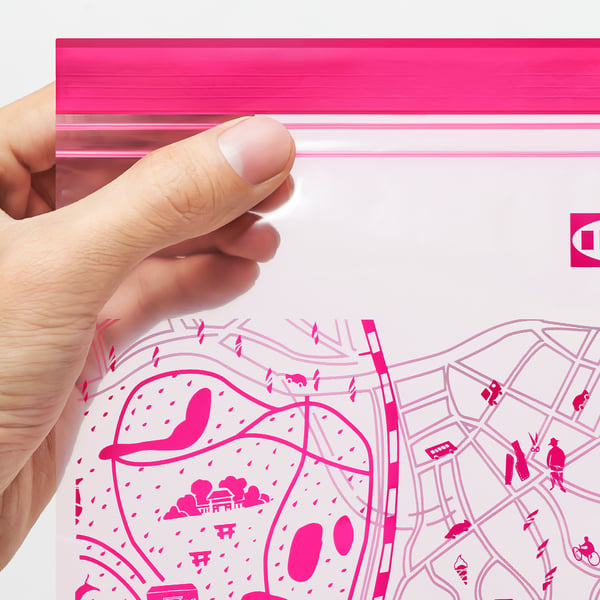 A hand holding a pink reusable sealable bag, shown partially open, highlighting its re-sealable feature.