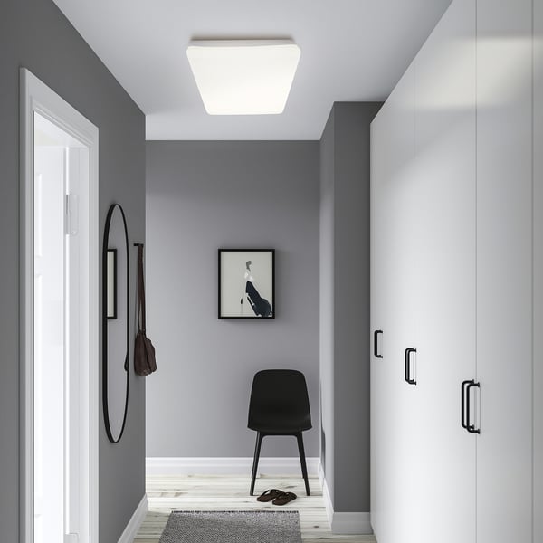 Modern entryway: grey walls, black chair & bag, rug, mirror left, picture right.