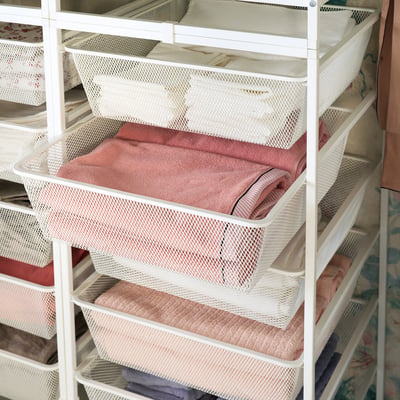 White metal storage rack with mesh drawers holding folded pink clothes. Neat and organised design for efficient space use.