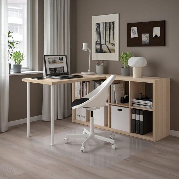 Modern home office with KALLAX storage, adjustable desk, laptop, bookcase, ergonomic chair, plants, minimalist decor.