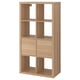 A KALLAX storage unit in light oak colour. It a rectangular shape with several open and closed compartments for versatile storage.