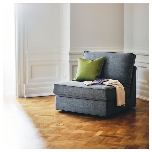 Modern grey sofa-bed with green pillow, wooden floor, minimalist design.