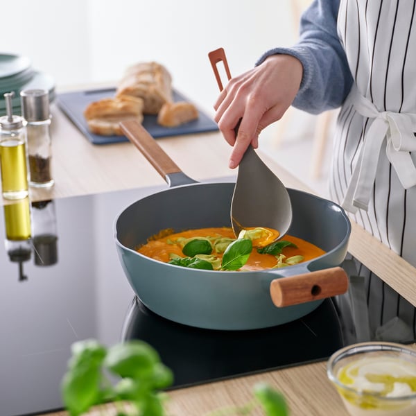 Person serving orange soup with colourful ergonomic deep spoon.