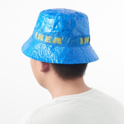 Person wearing a blue bucket hat with yellow text, offering sun protection and easy to carry.