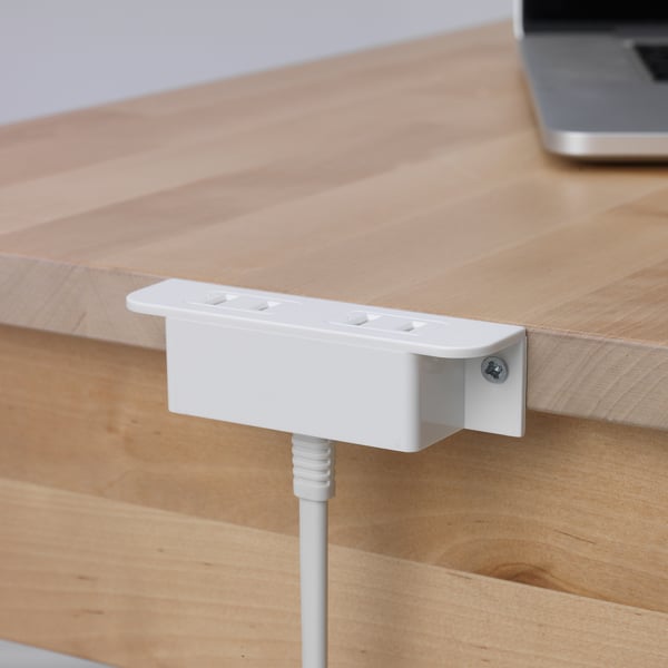 Wooden desk with white integrated power socket, securely mounted with a visible cable below.